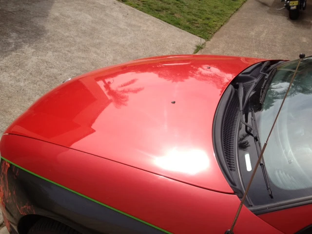 Red vehicle bonnet before paint correction